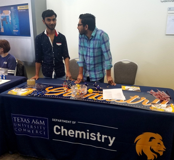 two students at Mane Event chemistry display table