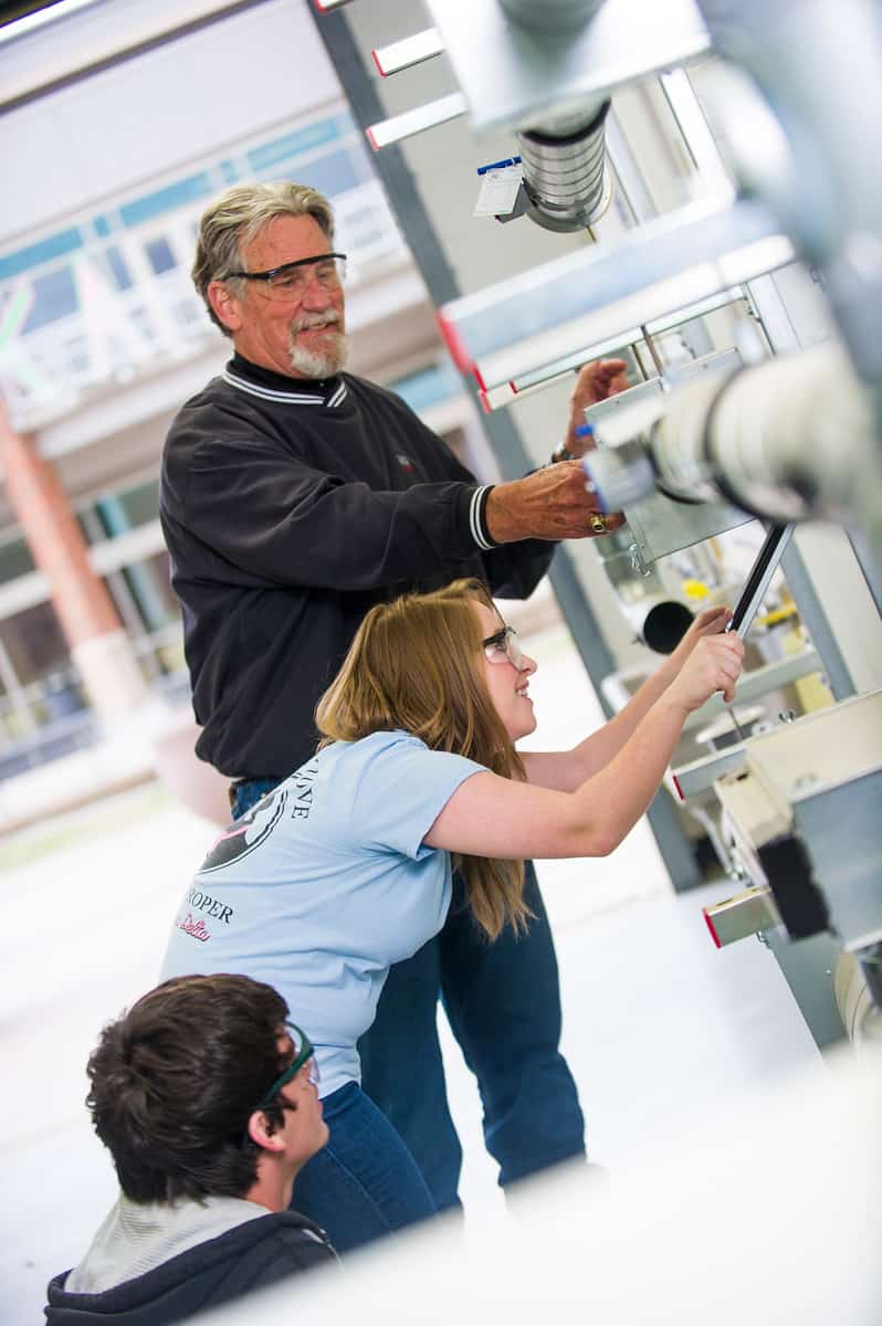 Engineering professor helping students with equipment