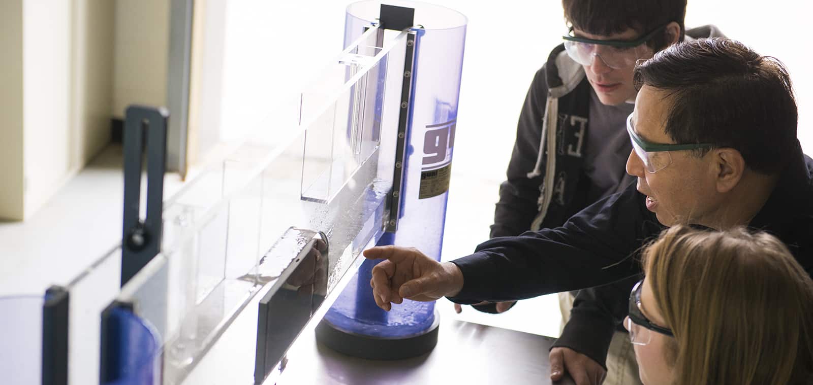 Professor and students looking at lab equipment