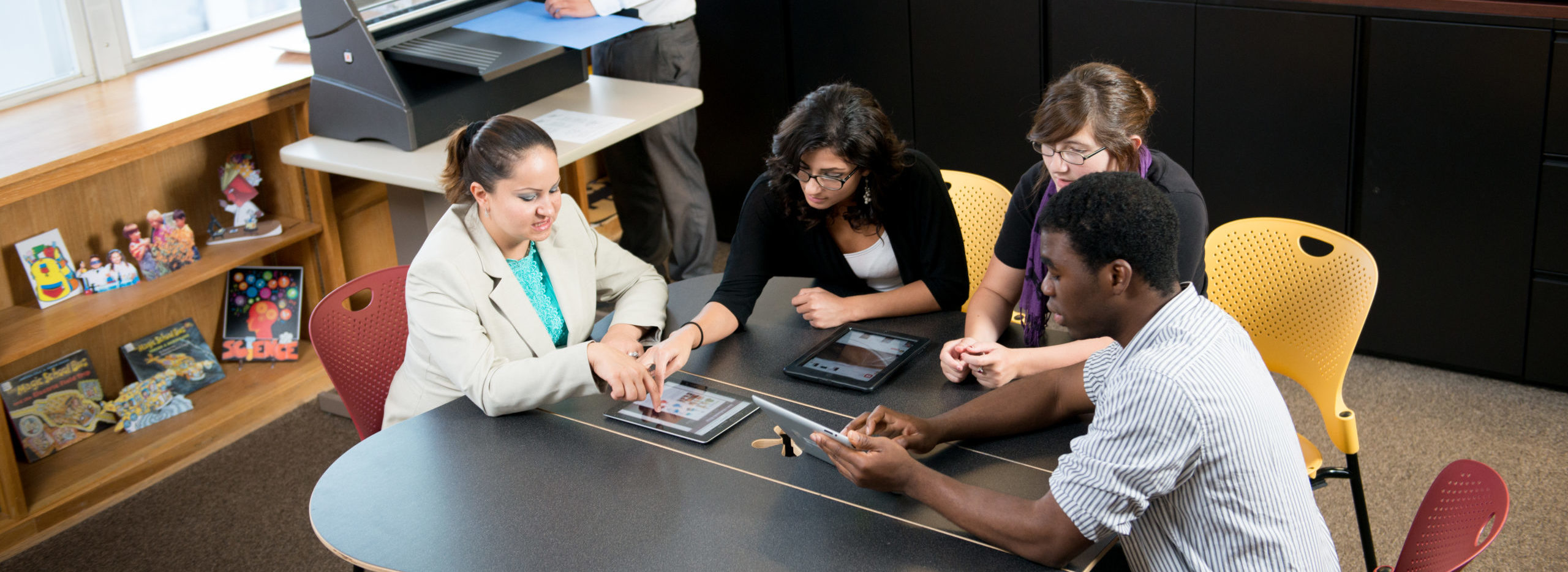 Group of students around table using tablets