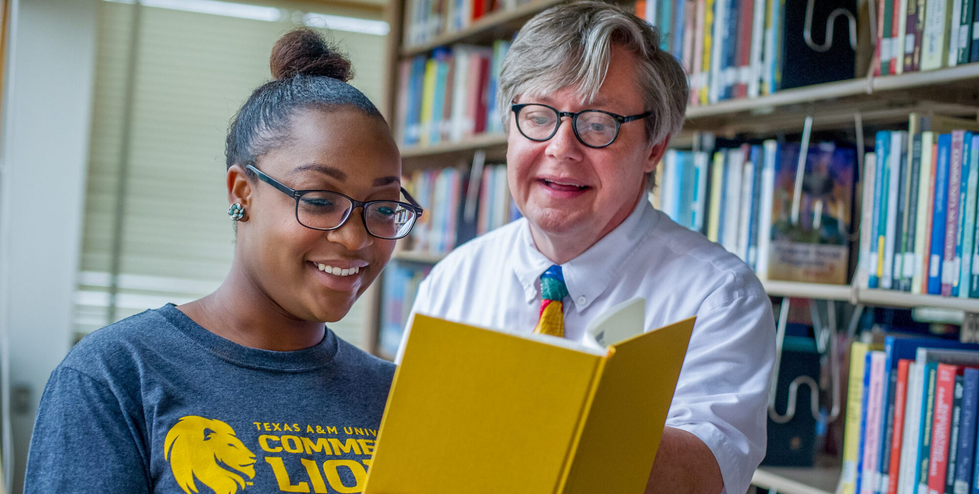 woman and man looking at big yellow book.