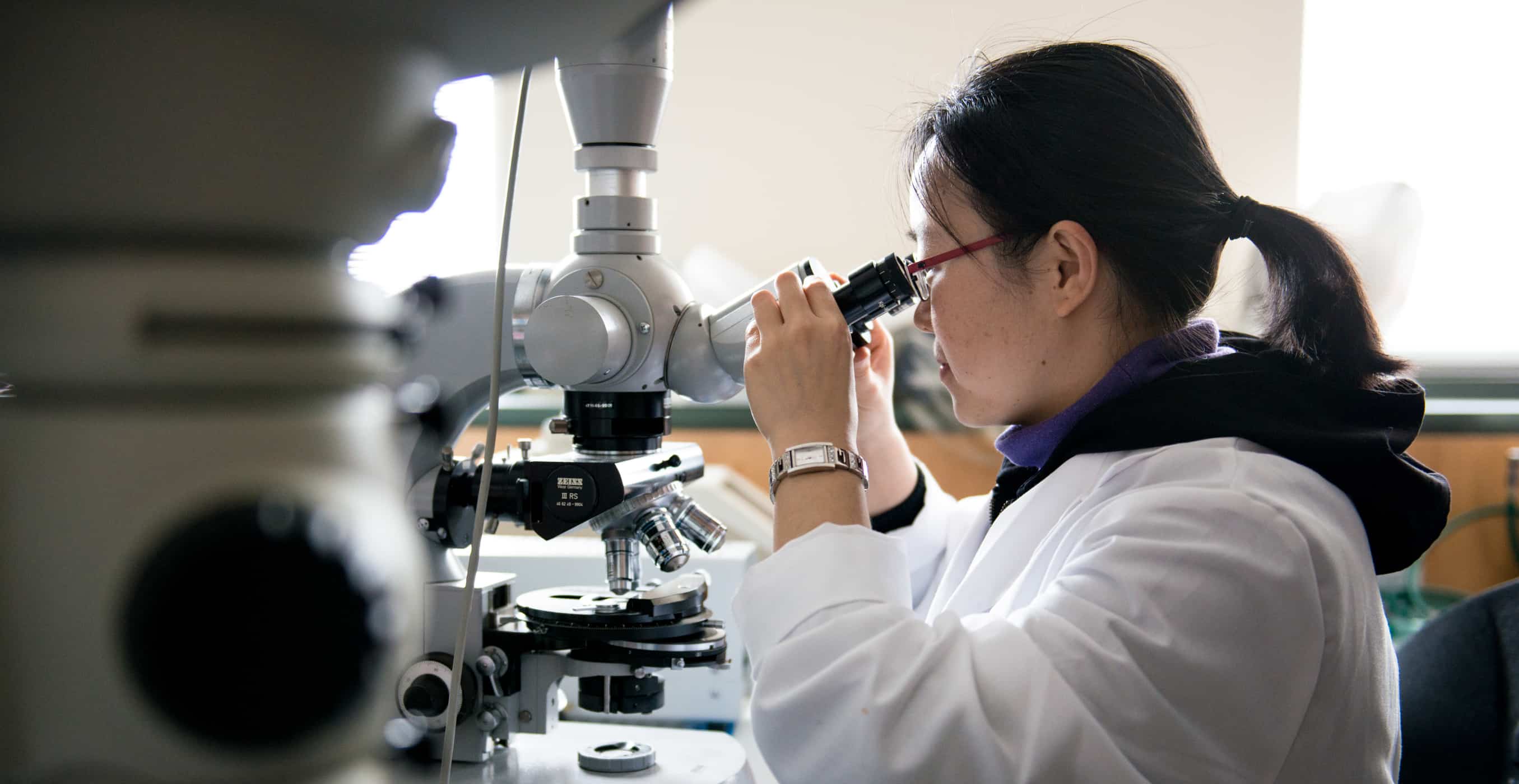 Student looking into microscope in Biology lab