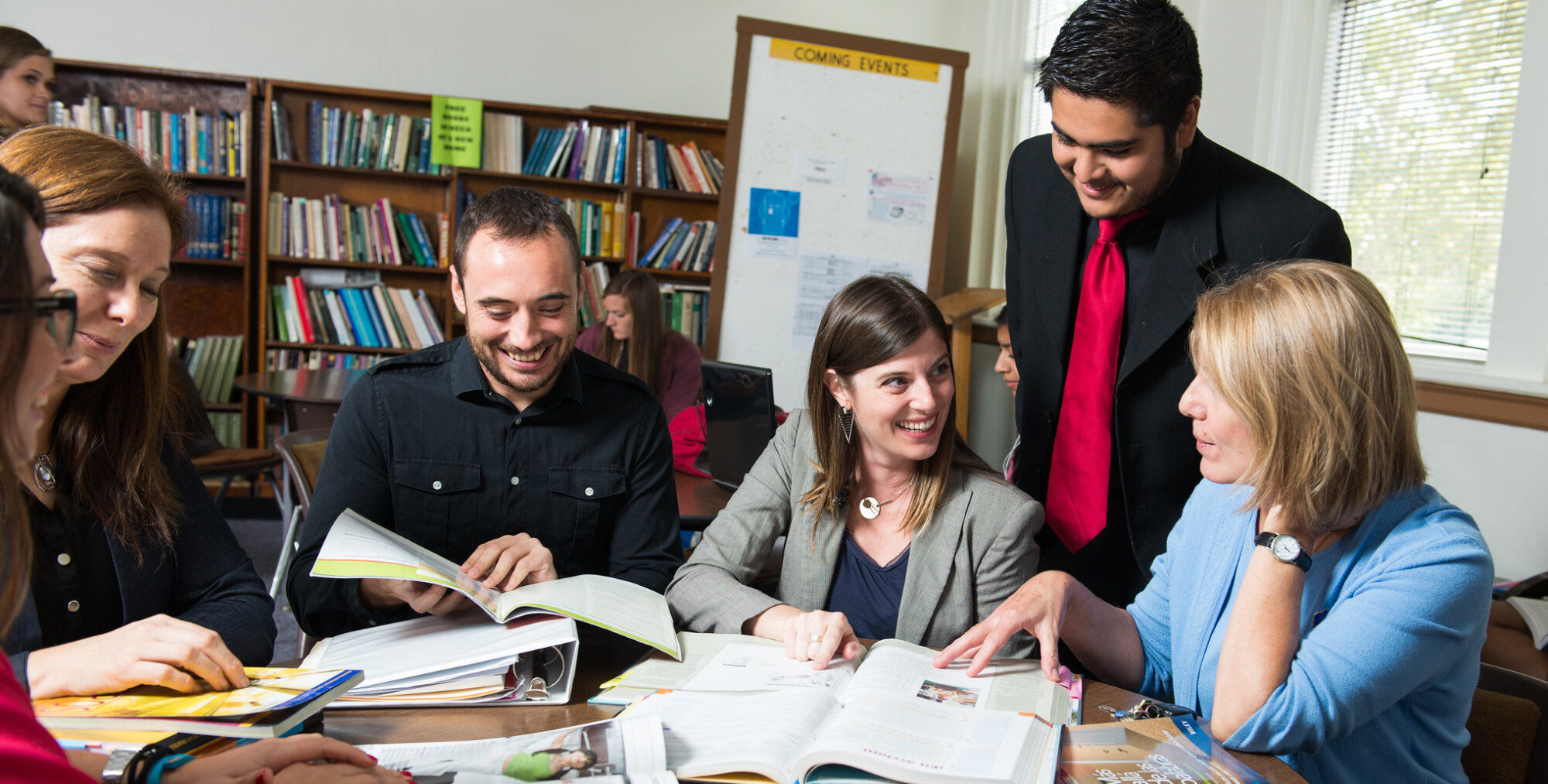 Group of students around a table studying Spanish books.