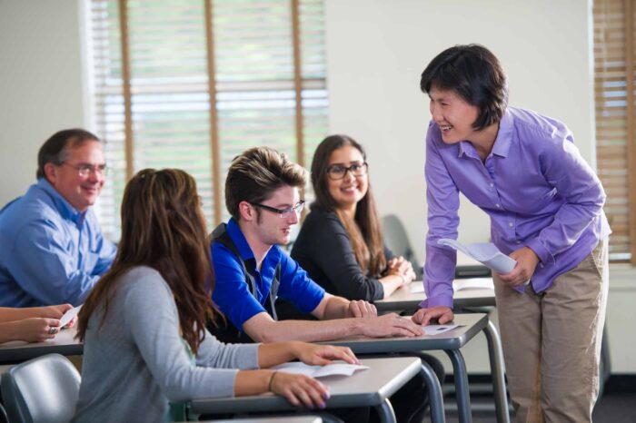 A professor interacting with students in a classroom.