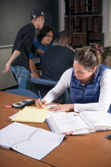 A female student completing school work on a desk in a classroom.