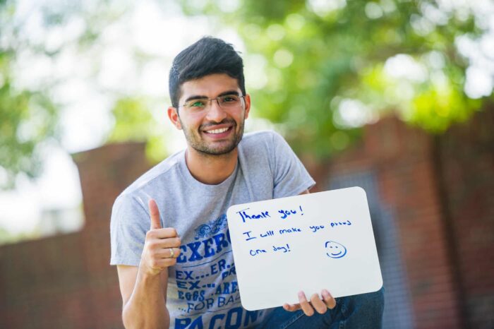 Person Holding a white board says 'Thank you! I will Make you proud one day!'