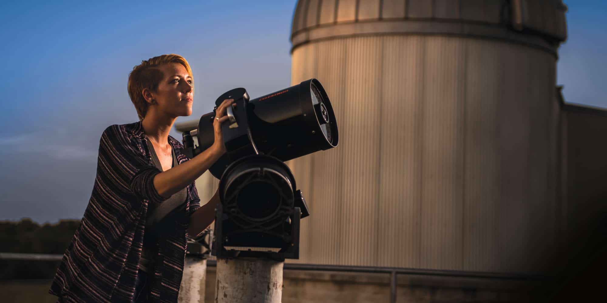 Image of a woman looking at a telescope.