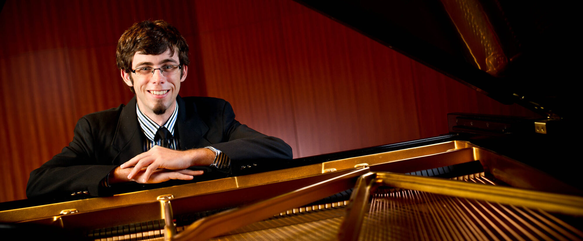 Man leaning on an open grand piano.