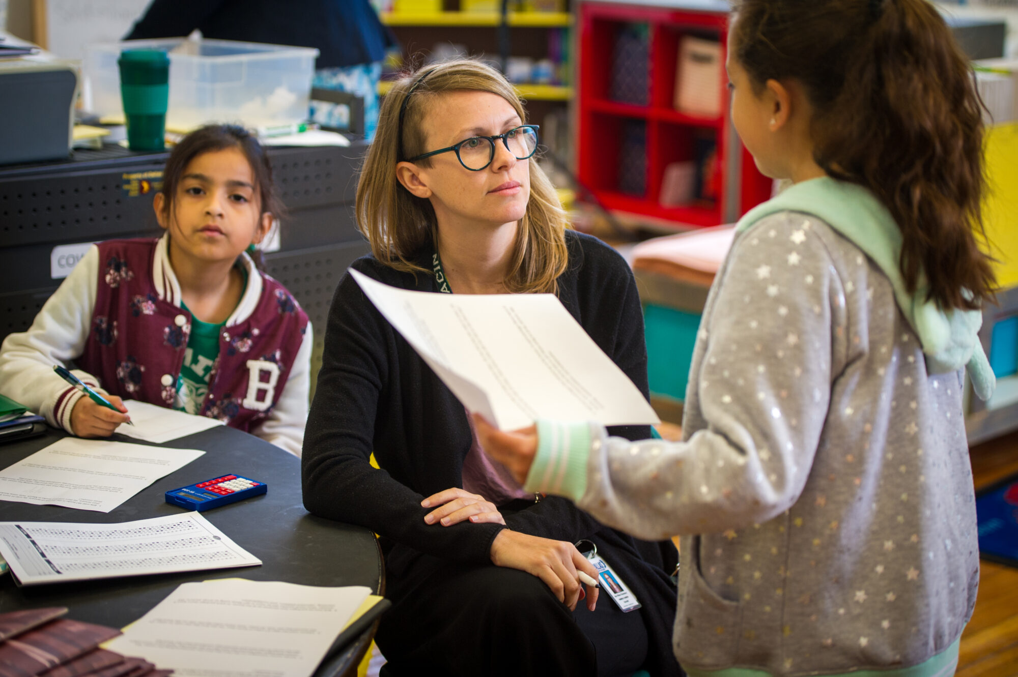 A female student teacher assisting two female enfant students.
