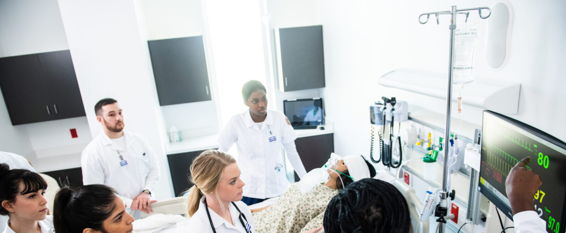 Future nurses studying patient life signs with teacher.