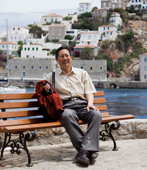 Jiaming Sun sitting on a bench on vacation.