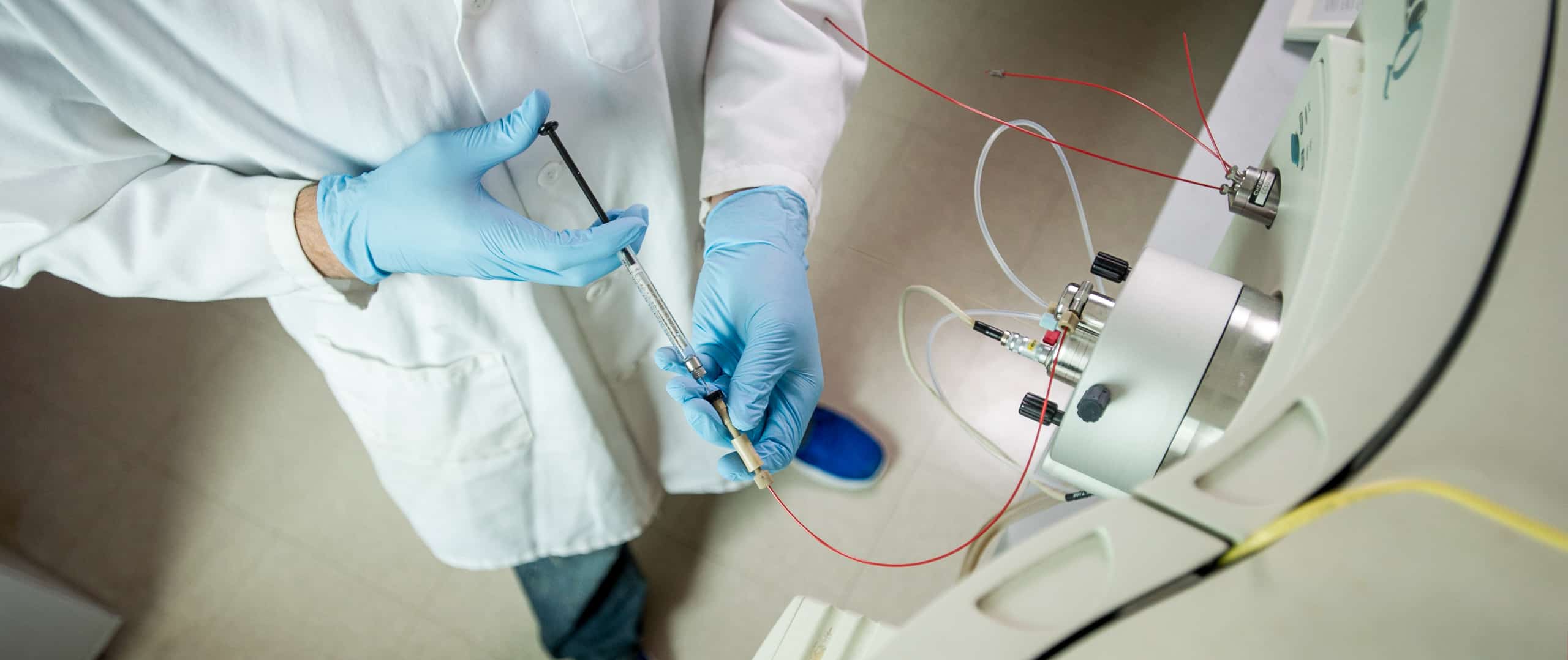 Chemist with personal protective equipment injecting a fluid into a machine