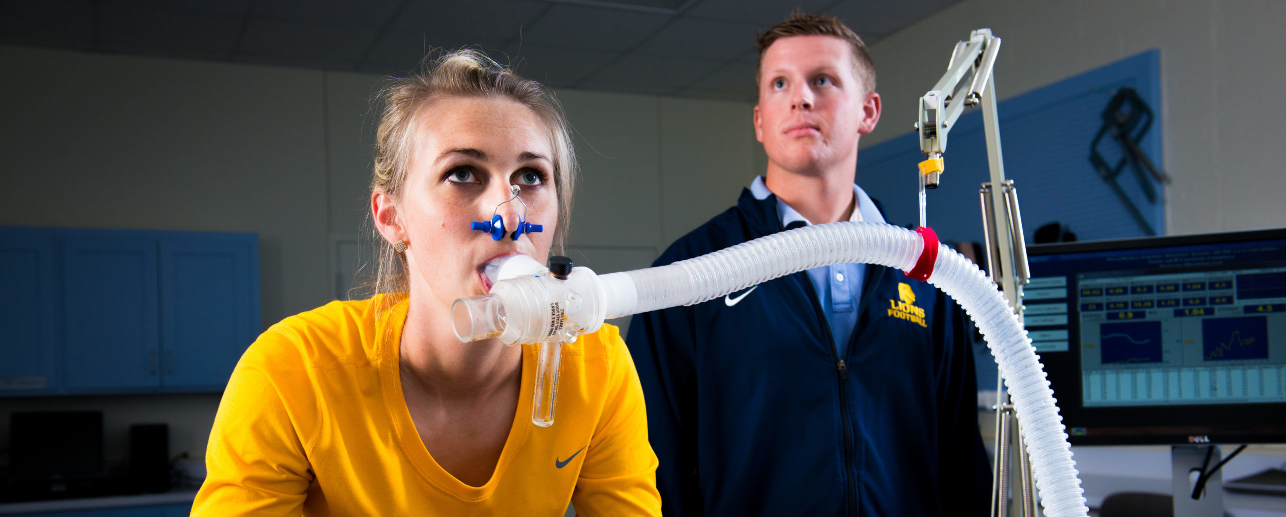 Young lady on exercise bike with ventilator tube measuring oxygen levels.