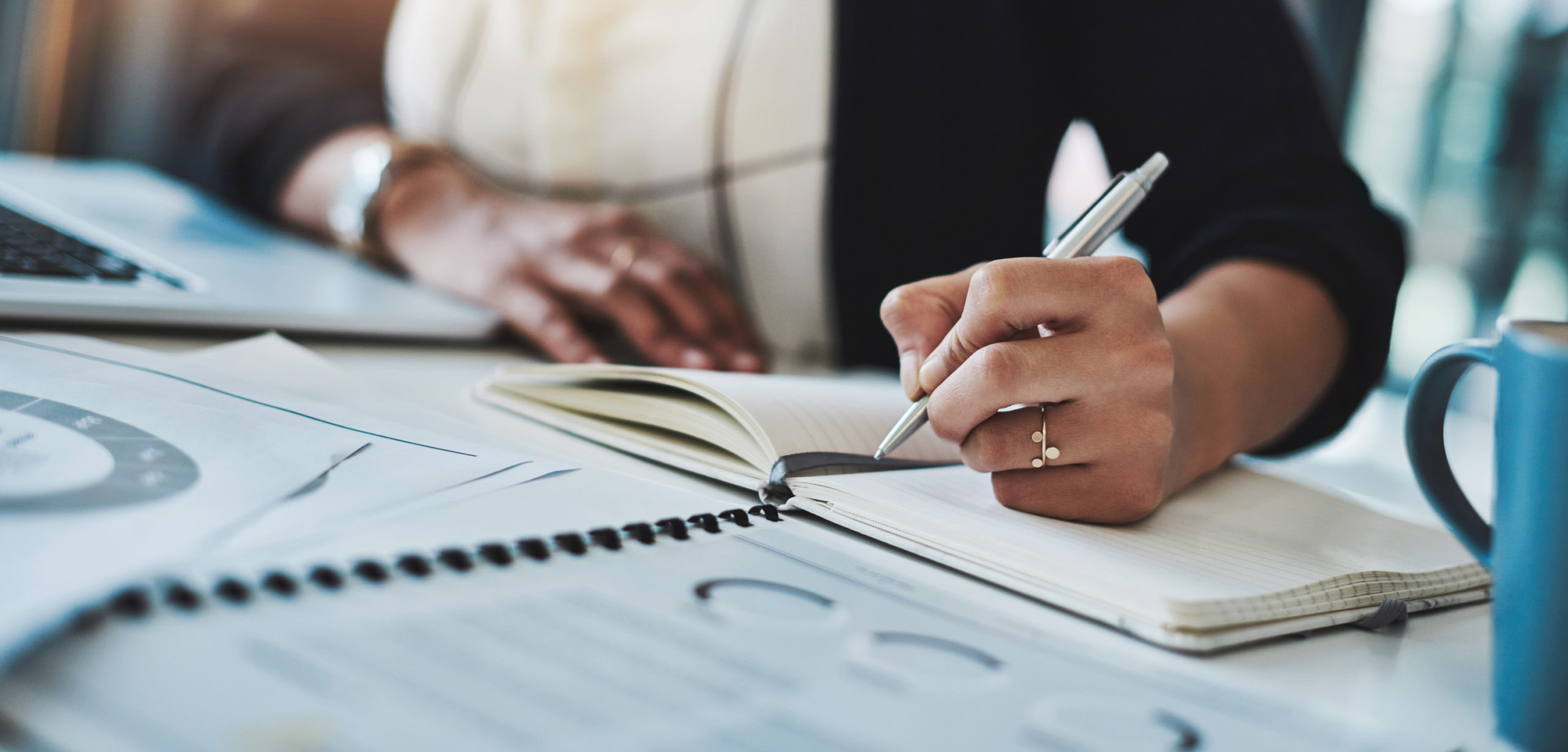 Cropped shot of a businesswoman making notes at her desk in a modern office.