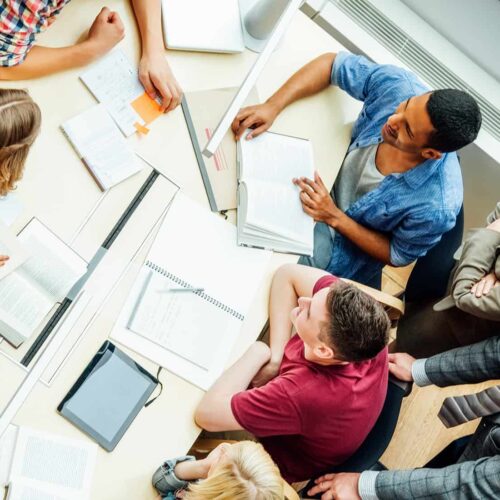 High angle view of professors and university students discussing at table in classroom