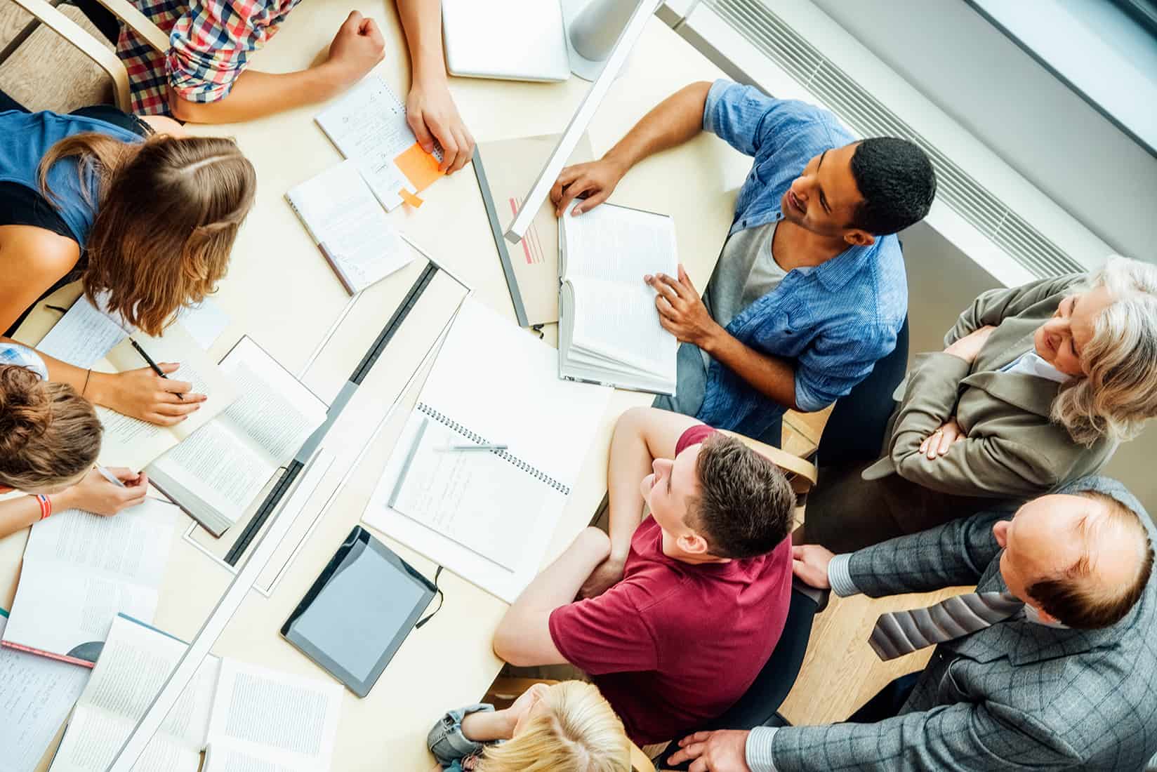 High angle view of professors and university students discussing at table in classroom