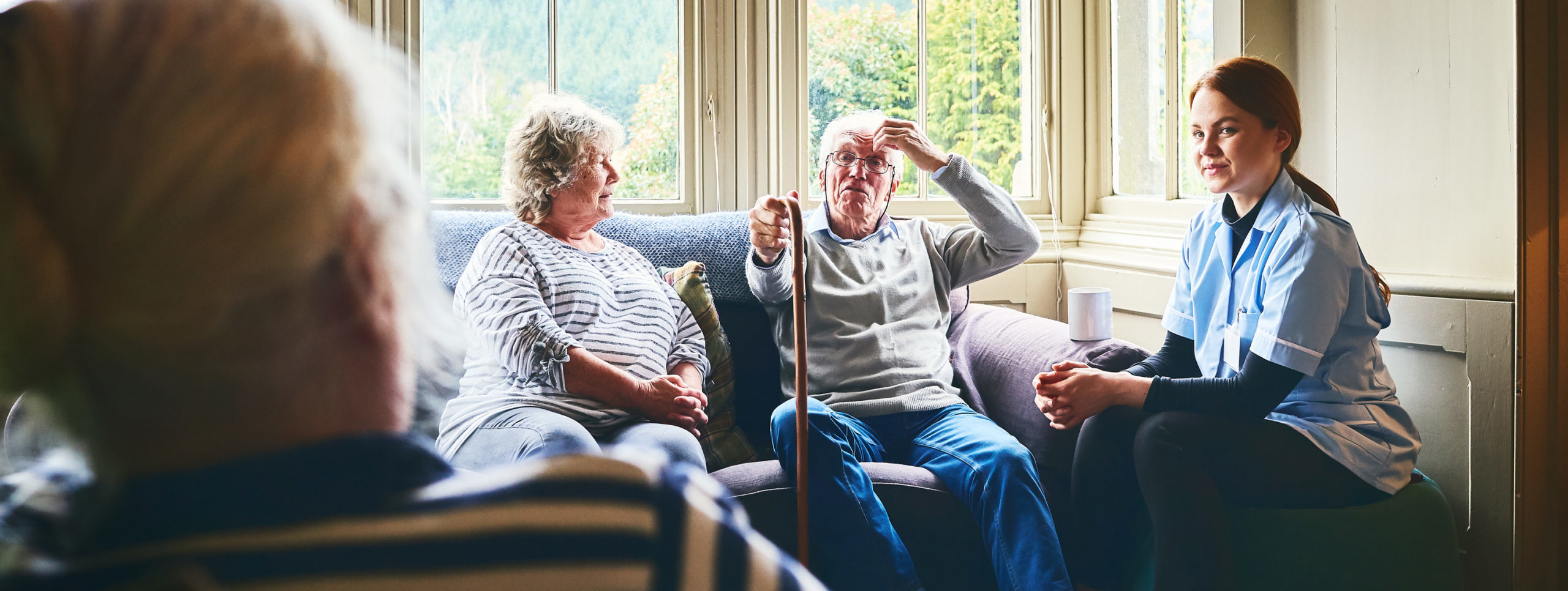 Female community nurse visiting senior people at care home.