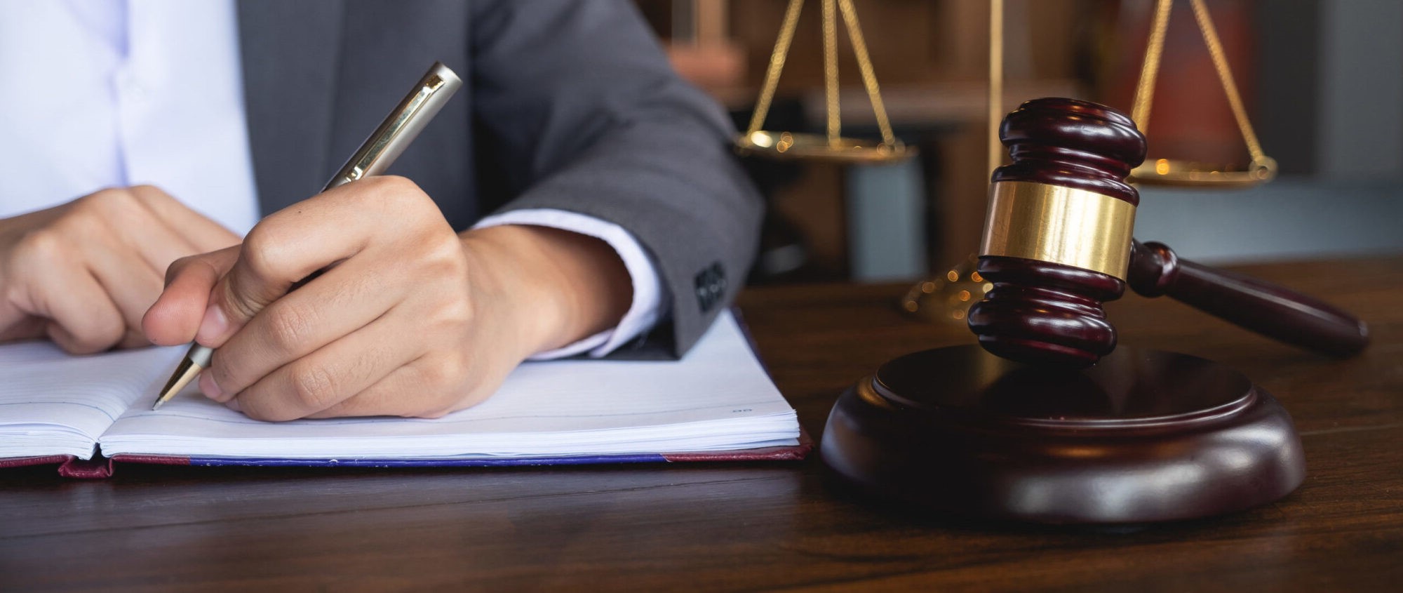 A person writing in a journal beside a judge hammer.