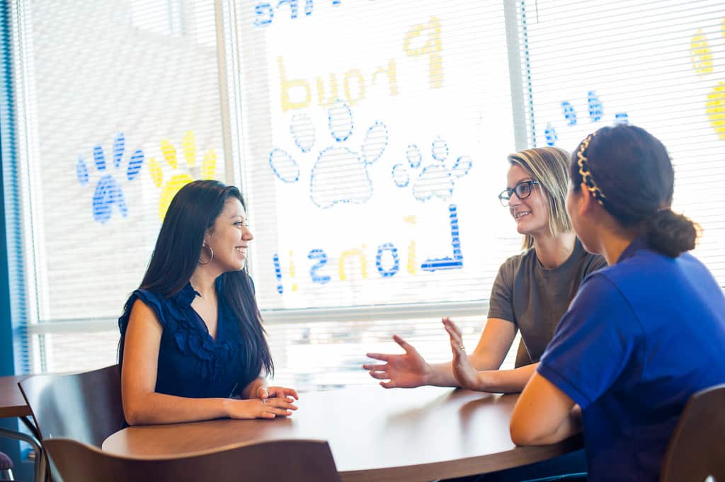 Students sitting down at a table having a conversation.