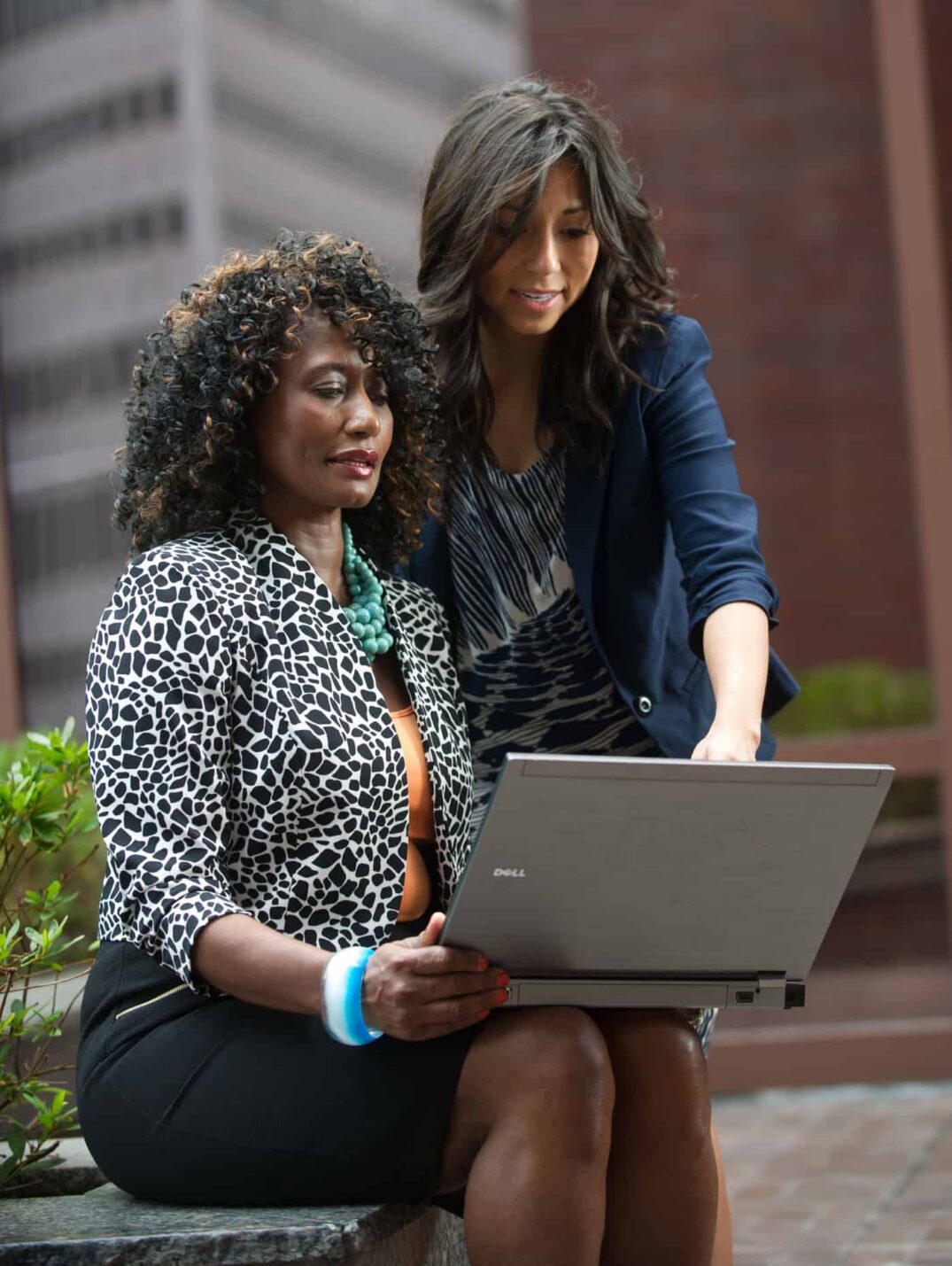 Two professionally dressed people discussing data on a laptop.