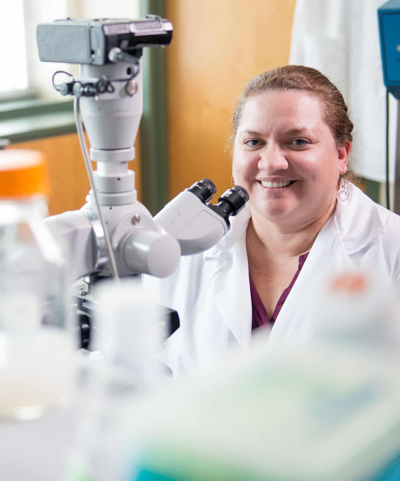 Biologist sitting next to microscope