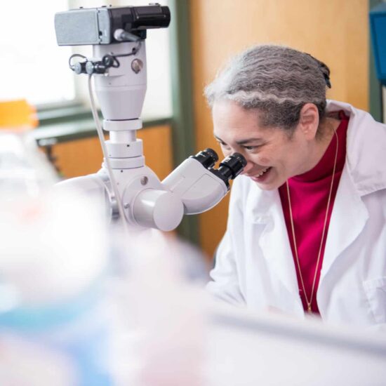 Scientist looking into microscope in Biology lab