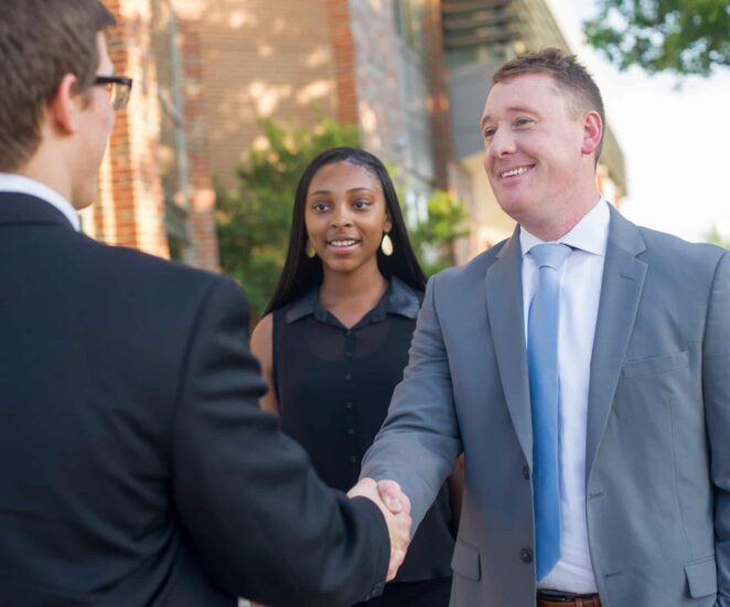 Business dressed group engaged in handshake.