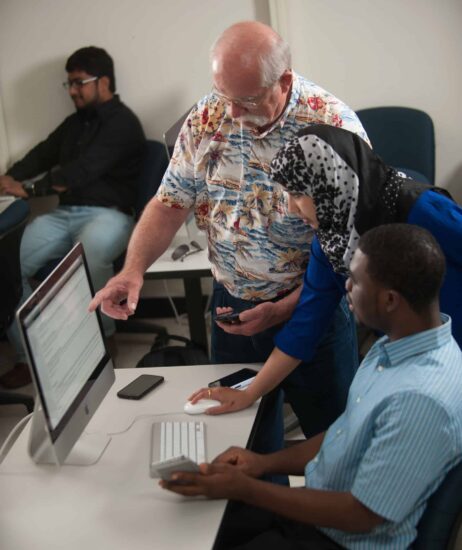 Computer science professor helping student at computer