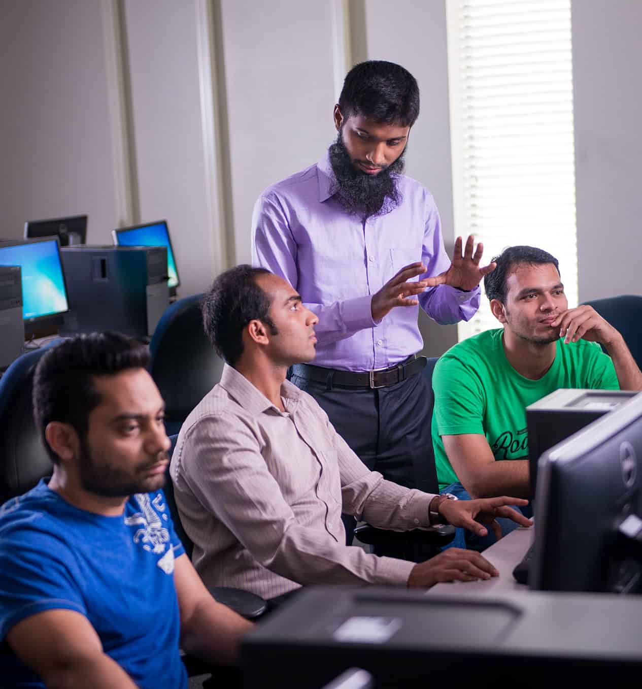 Professor helping three students at computers