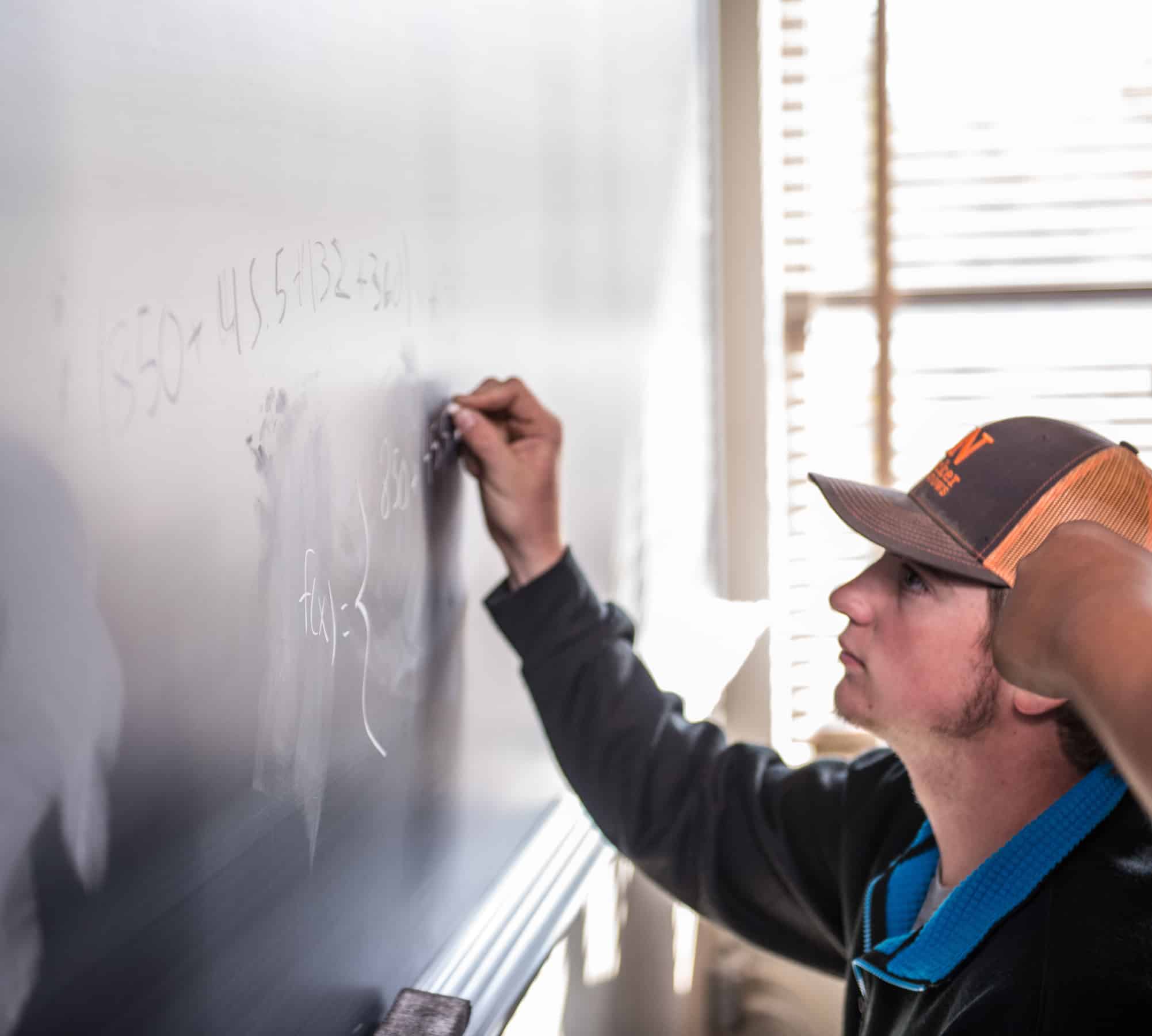 Math student working out problem on chalkboard