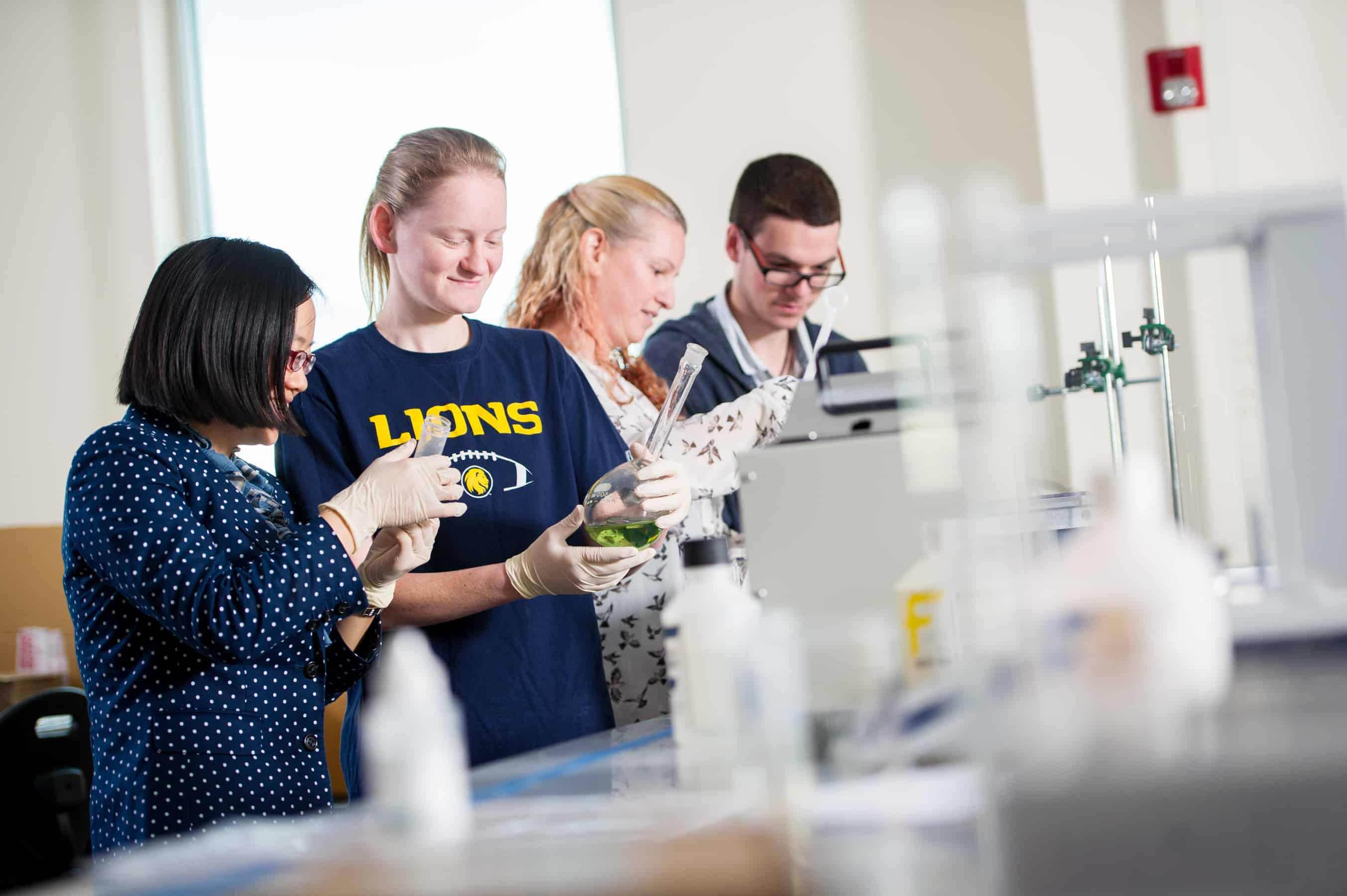 Chemists inspecting green liquid in flask