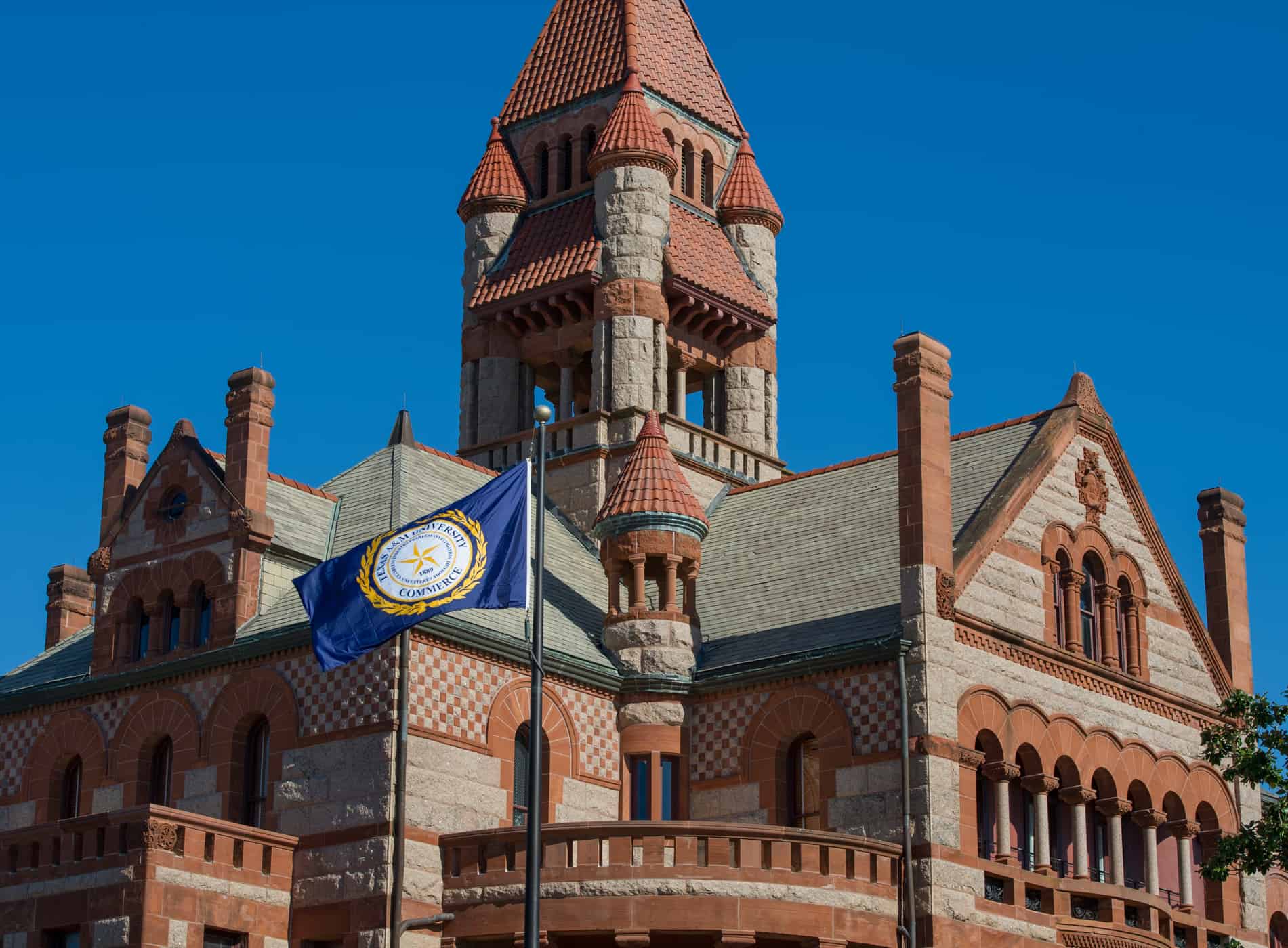 The A&M-Commerce flag in front of a building