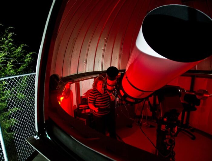 Students viewing stars with giant telescope.