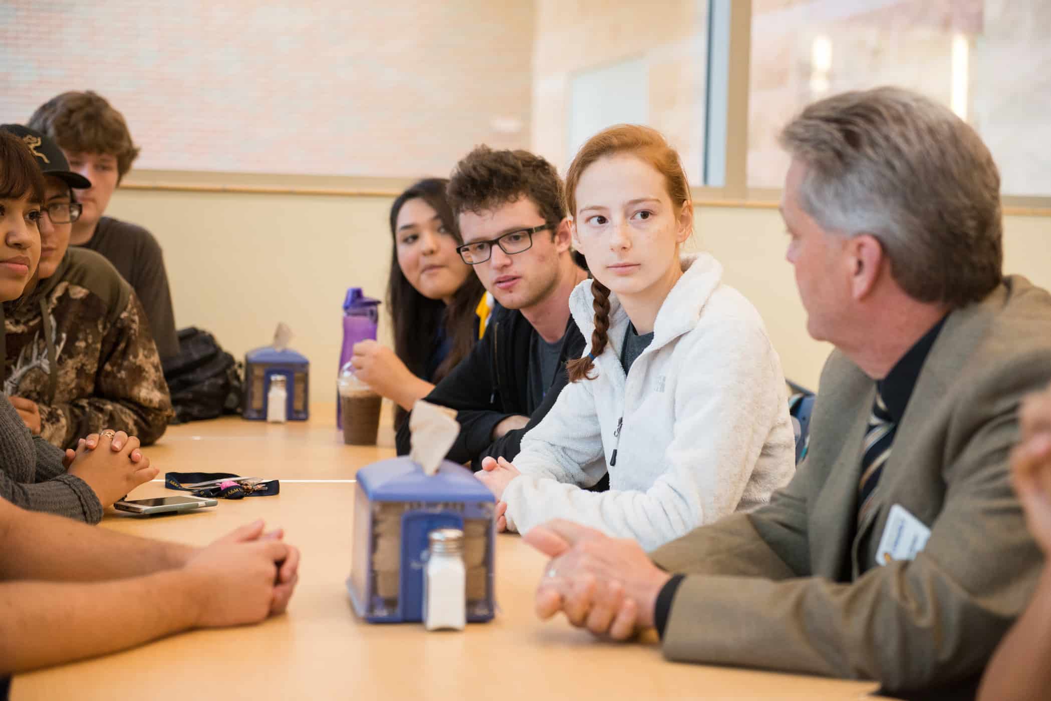 Professor sitting and talking with students at long table