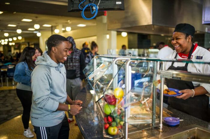 Two persons smiling to each other in cafeteria.