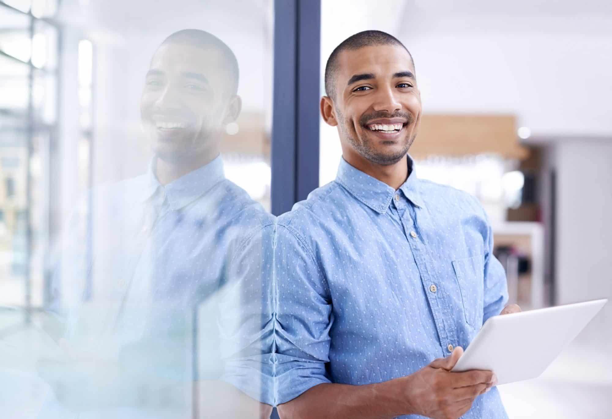 Man leaning against glass while holding tablet