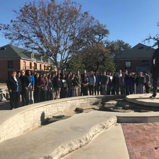 Students and faculty at a symposium event located outside.