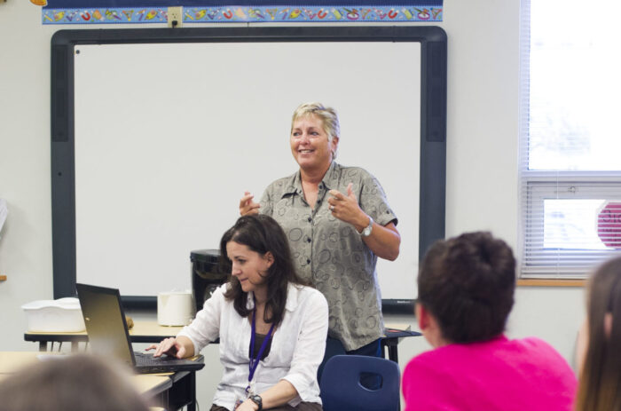 Teacher instructing a group in a classroom.