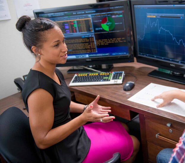 Student talking in front of computer monitors