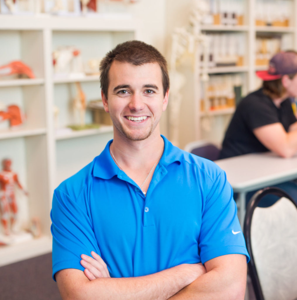 Health Human Performance student smiling at the camera with arm crossed.