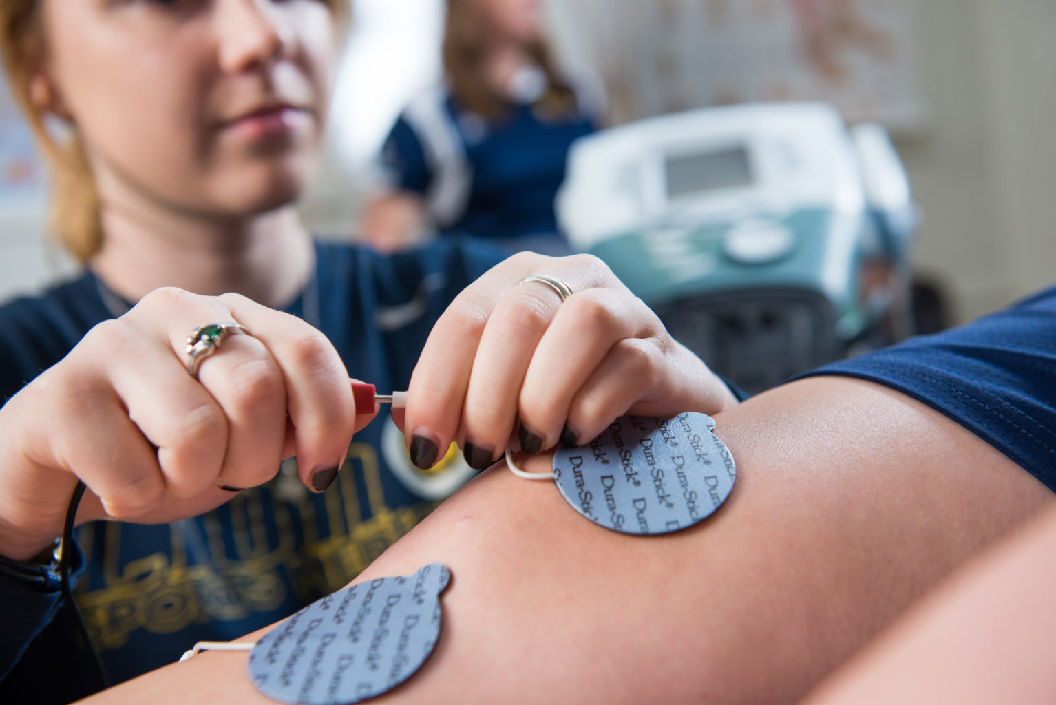 Woman putting electrodes on an athletes legs