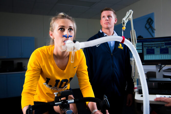 Young lady on exercise bike with ventilator tube measuring oxygen levels.