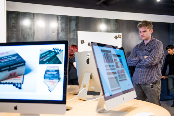 Mac computers showcasing digital media in a gallery.