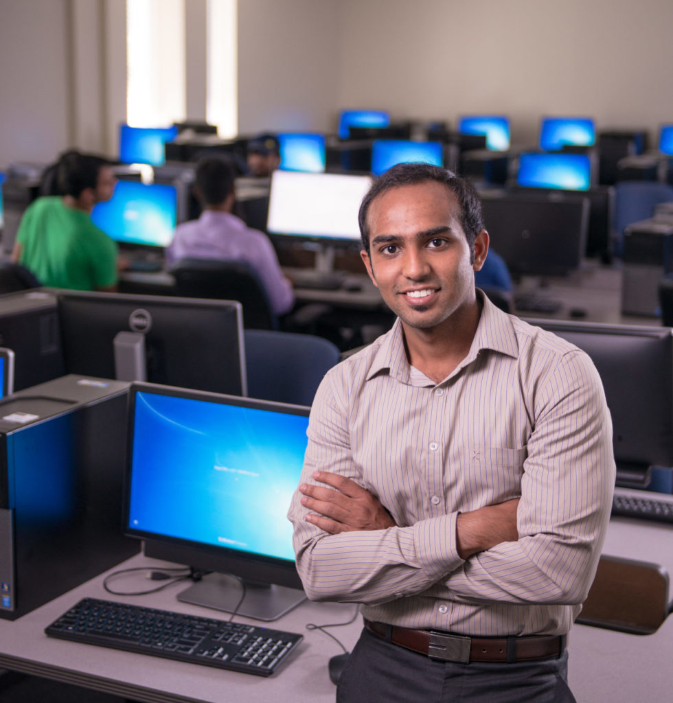 Man standing in front of a computer in a lab.