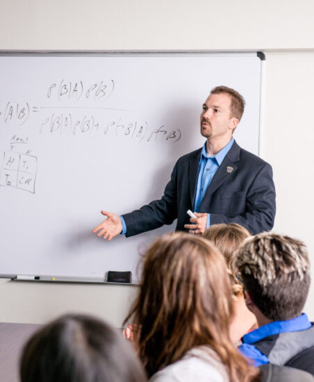 Male faculty member speaking to class.