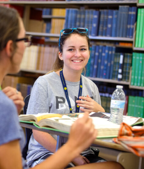 Two girls in the library studying their textbooks.