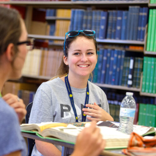 Two girls in the library studying their textbooks.