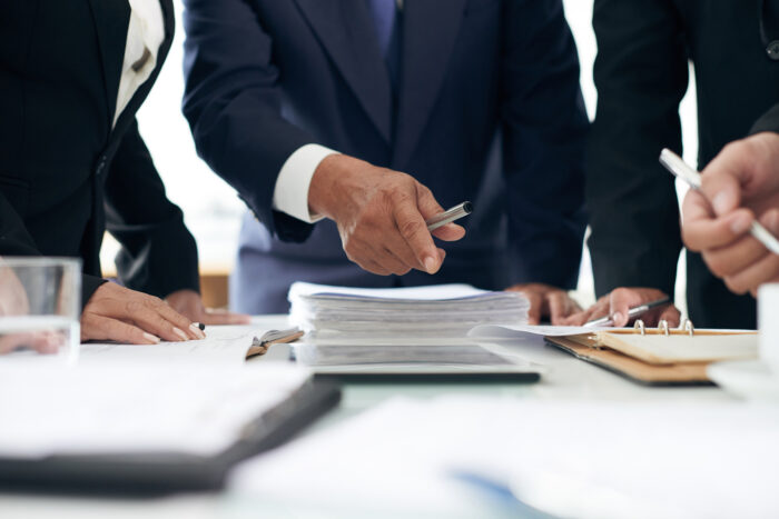 Two males and a female dressed nicely looking at legal documents.