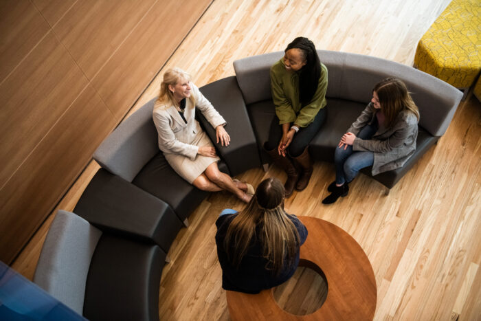 A teacher talking to a small group of student in the common area in the new health sciences building.