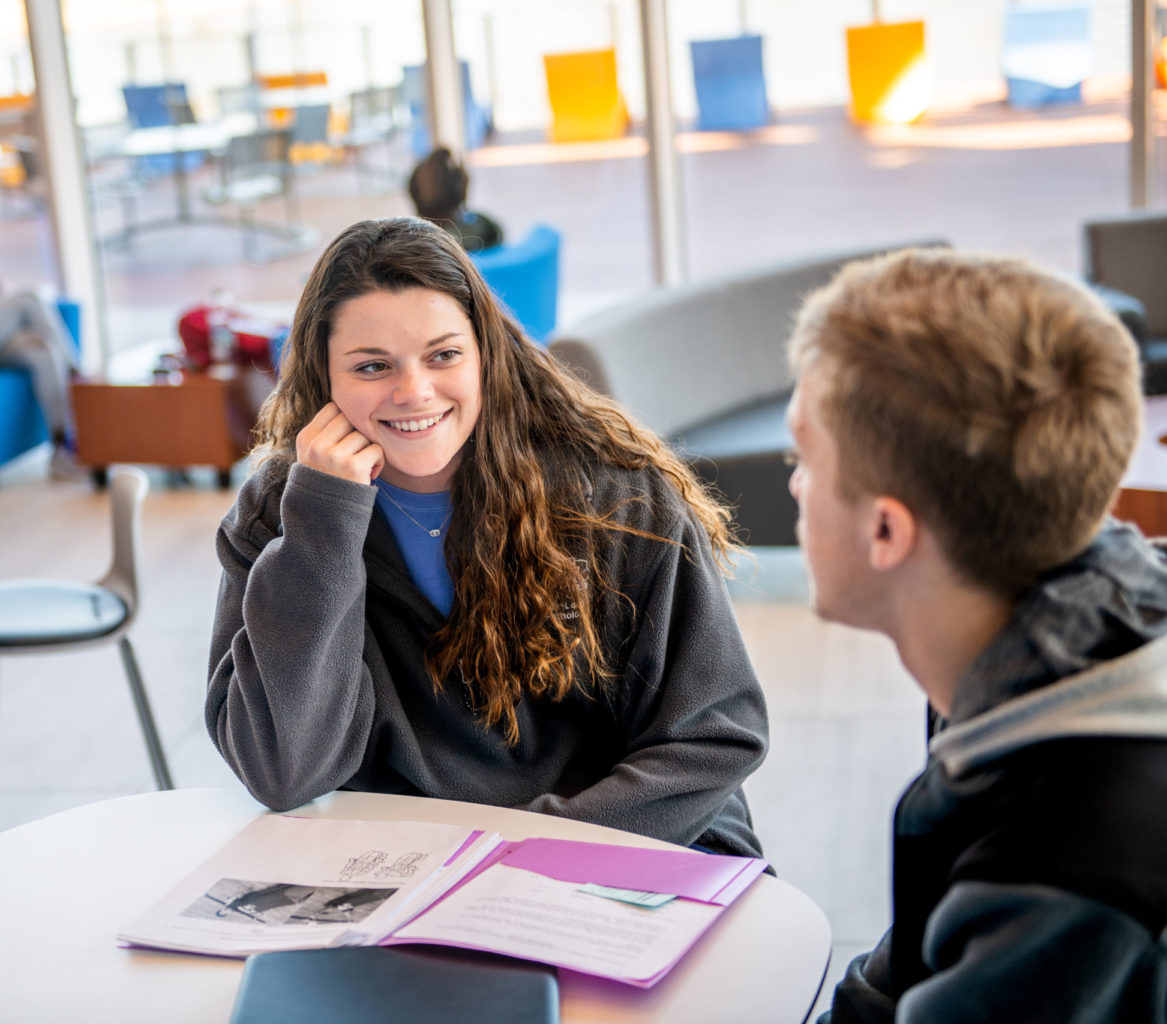 Young woman speaking with man in classroom environment